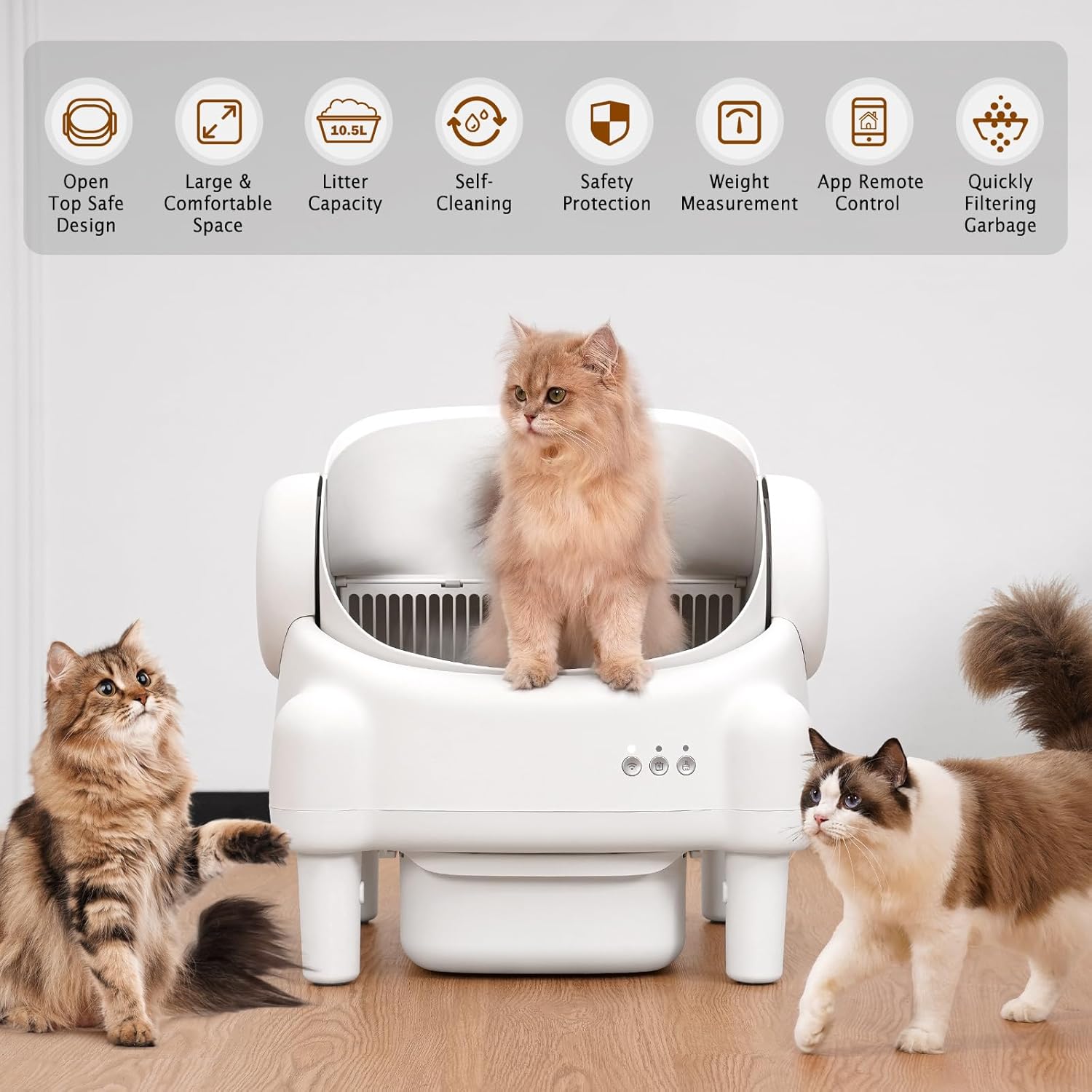White self-cleaning litter box with cats around it on a wooden floor.